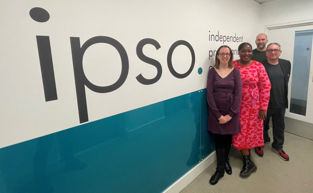 Staff from IPSO, SWU, and Campaign Collective stand in front of the "IPSO" sigh at the IPSO office in November 2022