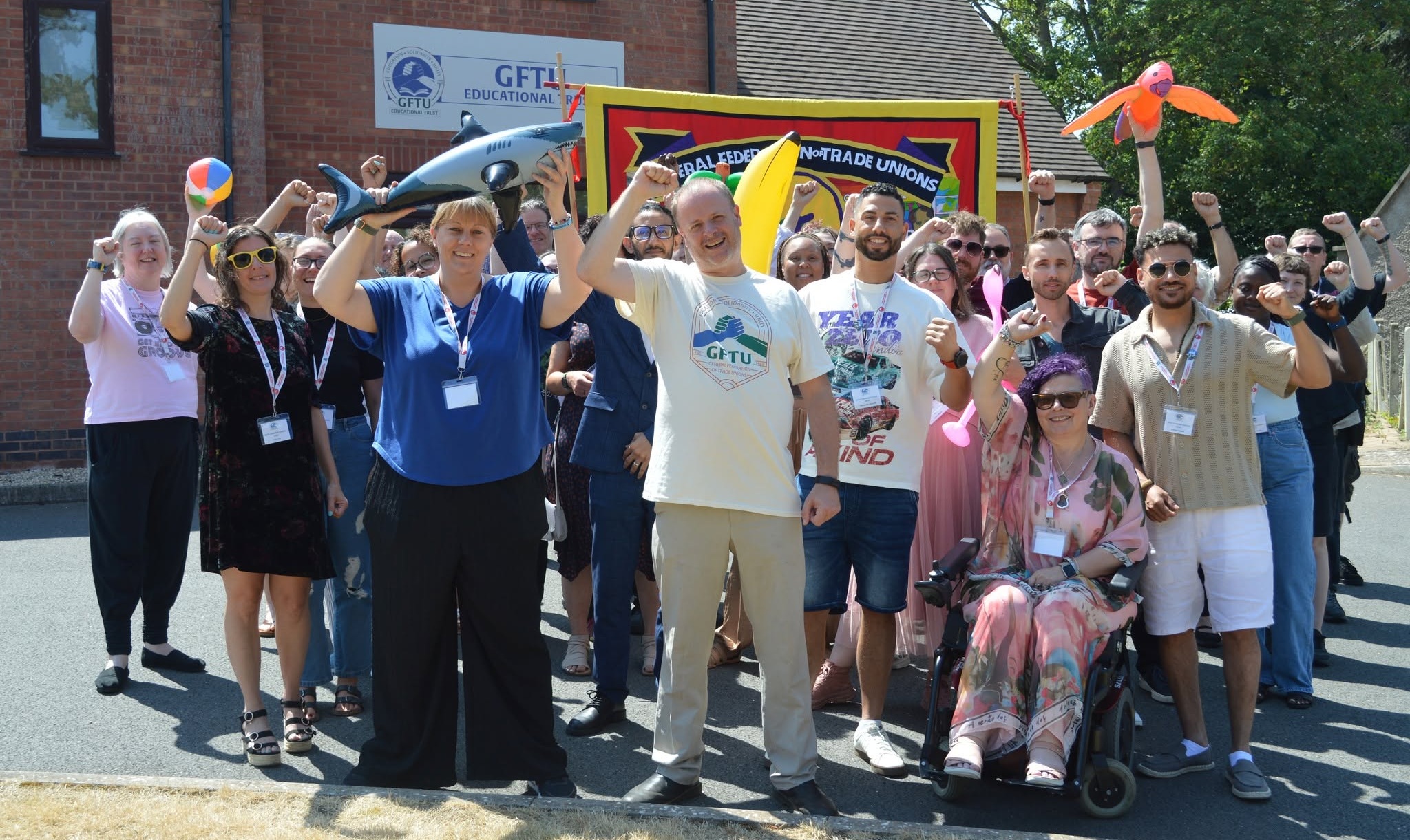 A photo of attendees of the GFTU Summer School 2026 raising their fists in solidarity in front of the GFTU banner